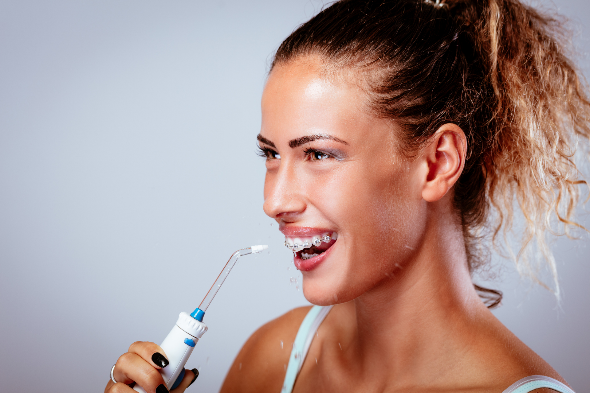 Woman using water flosser to clean teeth.