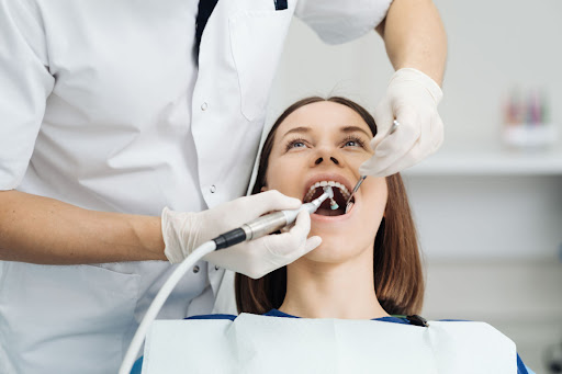 a woman at the dentist getting her teeth cleaned by a dentist